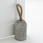 Concrete door stopper with a rope handle on a white surface.