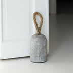Concrete door stopper with a rope handle on a white floor.