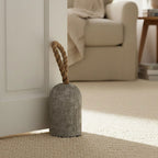 Concrete door stopper with rope on a carpeted floor in a home setting