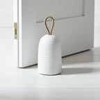 White textured door stopper with a rope handle on a white surface.