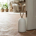 White textured doorstop with a rope handle on a brick floor in a home setting.