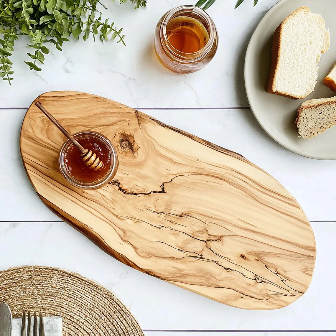 Wooden cutting board with honey and bread on a white surface