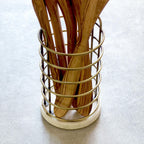 Wooden utensils in a gold metal holder on a light gray background