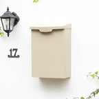 Beige mailbox on a white wall with a street number '17' and a light fixture.