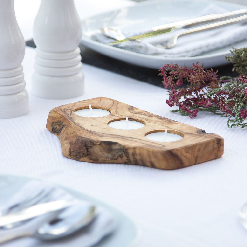 a 3 tealight holder made of olive wood with rustic bark on a white surface with wedding decor