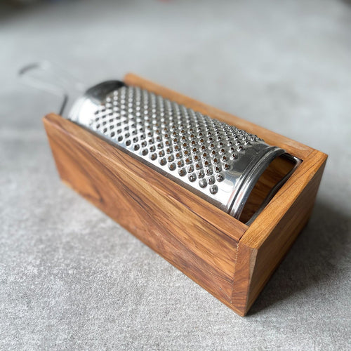 An Italian made cheese grater with a olive wood box, featuring a silver metal grating surface set within a rectangular wooden box.