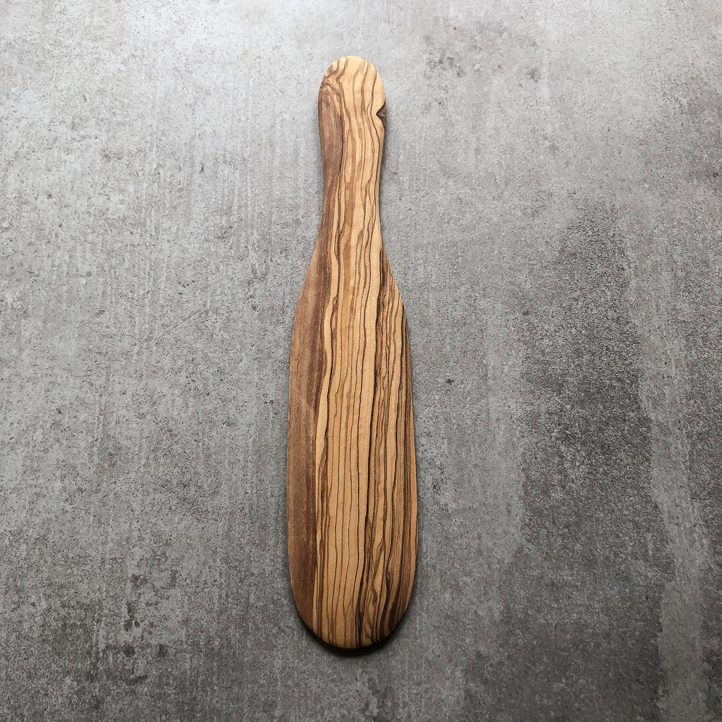 olive wood spatula resting on a grey surface