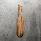 olive wood spatula resting on a grey surface