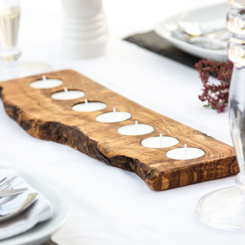 a  7 tealight holder made of olive wood with rustic bark on a white surface with wedding decor